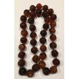 A BURMESE MYANMAR AMBER BEAD NECKLACE The knotted string of forty carved spherical translucent brown