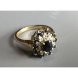 A 9CT GOLD, DIAMOND AND SAPPHIRE SET RING The central stone amongst a row of diamonds,