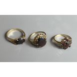 THREE 9CT GOLD AND GARNET SET RINGS To include a cluster ring with centre stone flanked by eight