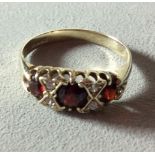 A VINTAGE 9CT GOLD, GARNET AND WHITE SAPPHIRE RING Having three graduating garnets interspersed with