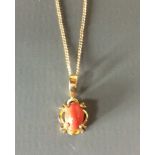 A 9CT GOLD AND CORAL PENDANT Single cabochon cut coral held in a pierced design and suspended from a