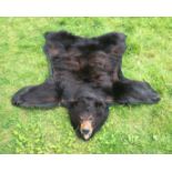 A LATE 20TH CENTURY TAXIDERMY BLACK BEAR SKIN RUG WITH MOUNTED HEAD