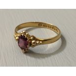 A 22CT GOLD AND AMETHYST RING The single oval cut stone set on a beadwork decorated bezel. (amethyst