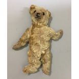 AN EARLY 20TH CENTURY MOHAIR TEDDY BEAR With glass eyes and movable limbs.