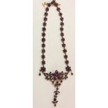 AN EARLY 20TH CENTURY YELLOW METAL AND GARNET NECKLACE Having a row of daisy style clusters