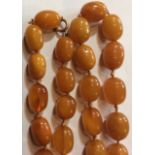 AN ANTIQUE NATURAL BALTIC AMBER NECKLACE The single strand of graduating oval beads on a yellow