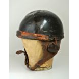 AN EARLY 20TH CENTURY MOTORCYCLE HELMET With leather chin strap and black finish, complete with