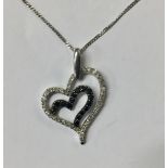 A 9CT WHITE GOLD AND DIAMOND HEART FORM PENDANT With a row of round cut diamonds centred by a