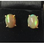 A PAIR OF YELLOW METAL AND OPAL EARRINGS Having oval set opals set into a four prong clasps with