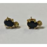 A PAIR OF YELLOW METAL, DIAMOND AND GEMSTONE EARRINGS Having an oval cut blue gemstone over a single