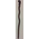 AN ORIENTAL SOFTWOOD CARVED SERPENTINE WALKING STICK Depicting a stylized dragon. (approx 98cm)