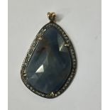 A DIAMOND AND SAPPHIRE PENDANT Having a faceted blue gemstone contained within a row of round cut