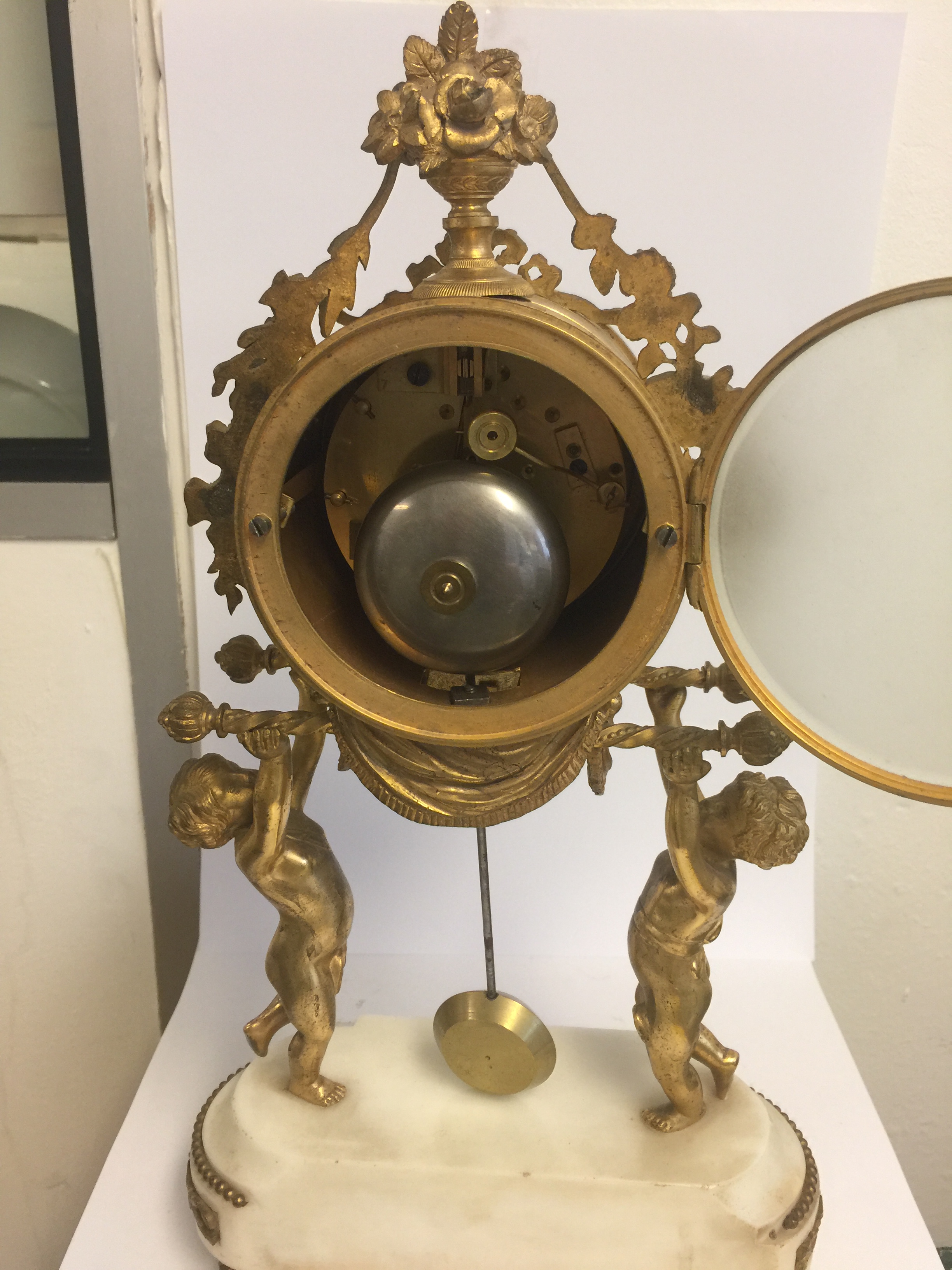 A 19TH CENTURY GILT BRONZE AND WHITE MARBLE DRUM CLOCK Held aloft by two putti. (38cm x 21cm x 9cm) - Image 4 of 5