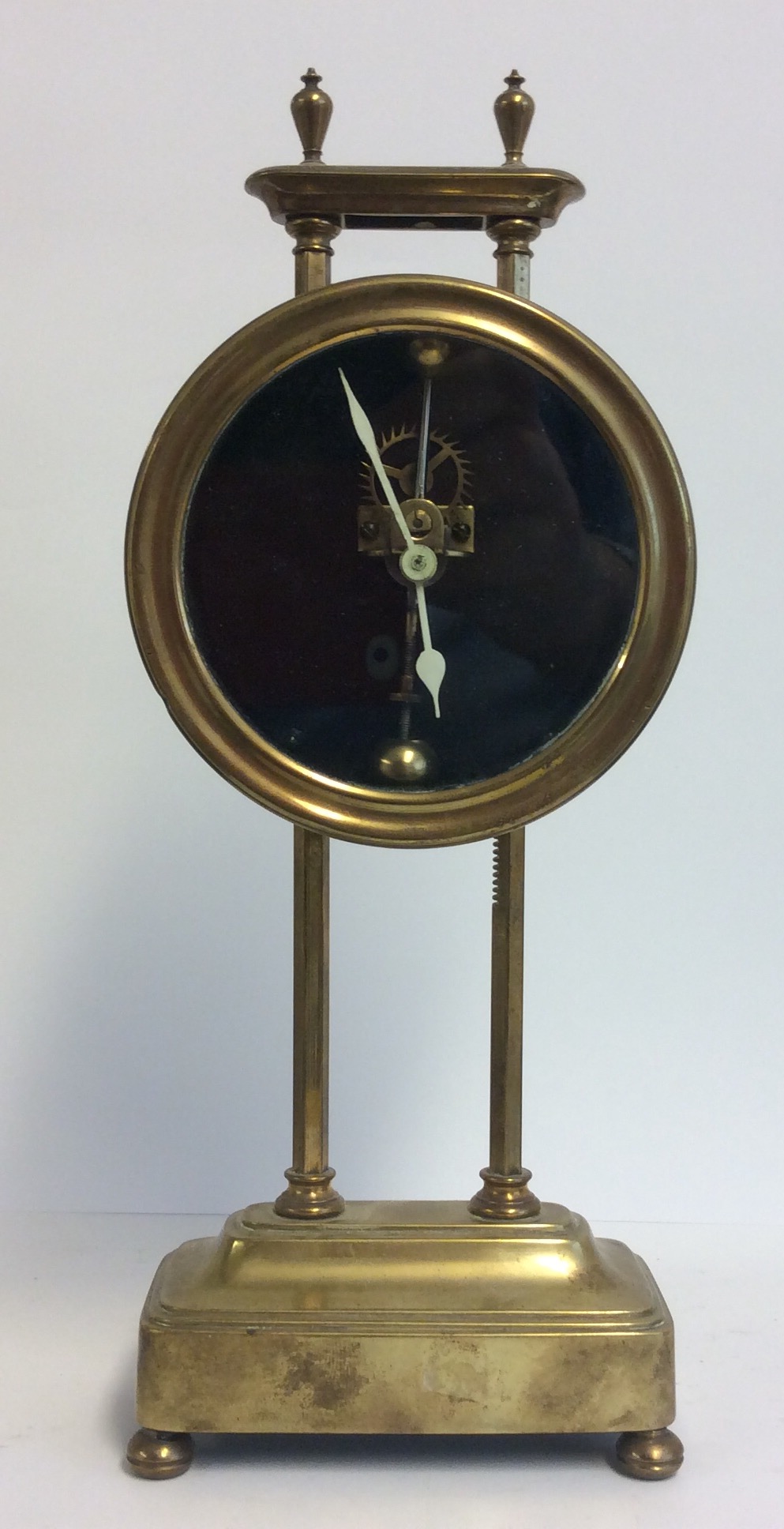 AN EARLY 20TH CENTURY BRASS GRAVITY CLOCK The circular dial with visual escapement, the frame marked