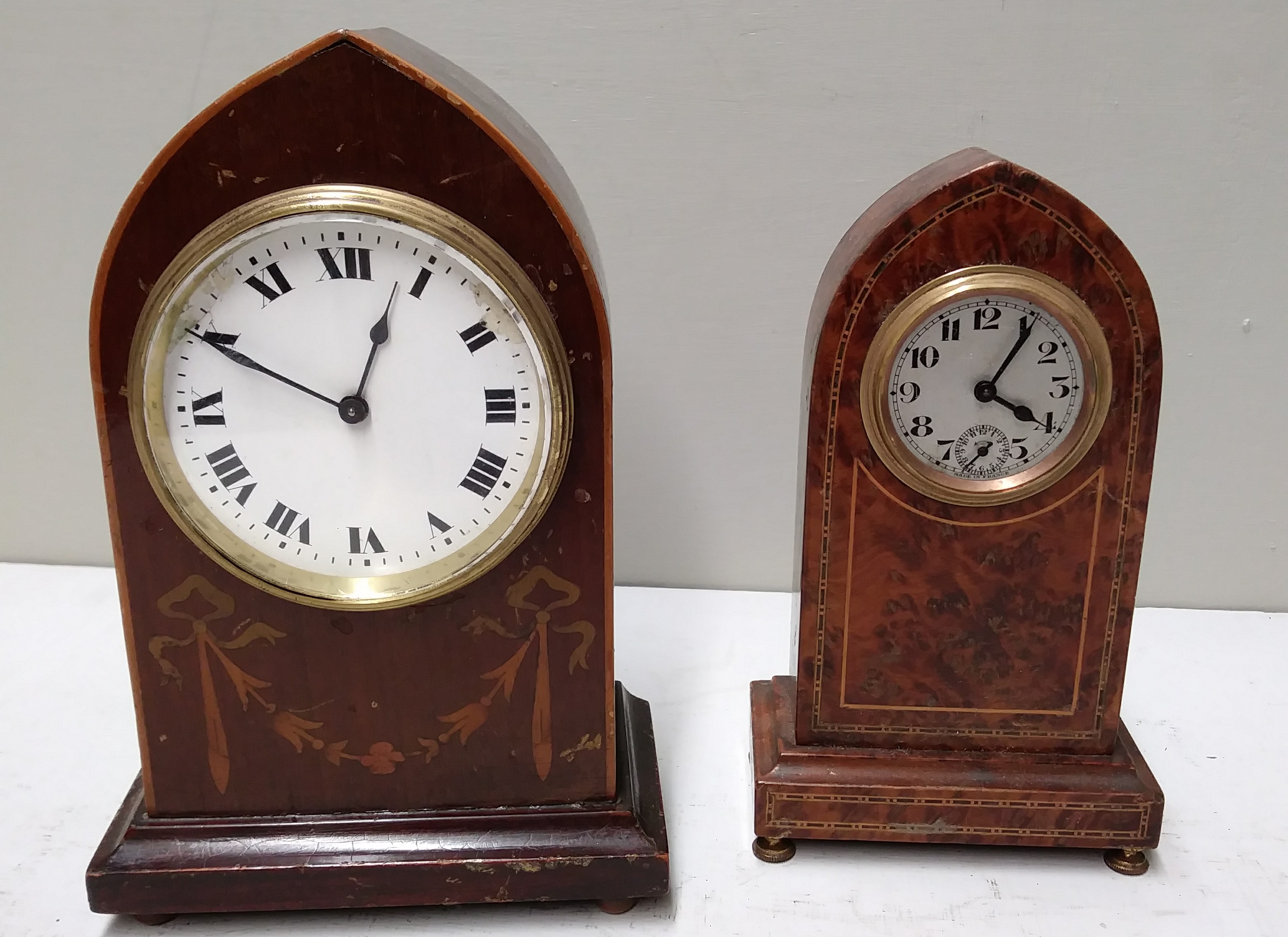 AN EARLY 20TH CENTURY AMBONA CASED CLOCK, along with another, both of gothic design. (largest 26 cm)