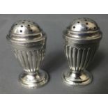 A PAIR OF VICTORIAN SILVER PEPPER POTS Of Neoclassical design with semi reeded body raised on