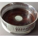 MILLENNIUM INTEREST, A SILVER AND OAK CIRCULAR WINE COASTER With pierced decoration and oak base,