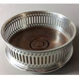 A 20TH CENTURY SILVER AND OAK CIRCULAR WINE COASTER With pierced decoration and oak base, hallmarked