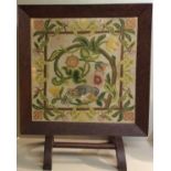 AN EARLY 20TH CENTURY WOOL WORK TAPESTRY FIRE SCREEN An exotic bird held within a floral border