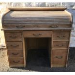 AN EARLY 20TH CENTURY LIMED OAK TAMBOUR ROLL TOPPED DESK Fitted with an arrangement of nine drawers.