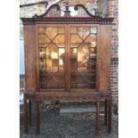 A GEORGIAN MAHOGANY BREAKFRONT BOOKCASE The pierced swan neck pediment centred with an urn, above