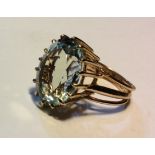 A VINTAGE YELLOW METAL AND AQUAMARINE RING The single oval cut stone held in a raised mount, on a