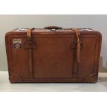 AN EARLY 20TH CENTURY TAN LEATHER SUITCASE With polished chrome locks , straps perished. (75cm x