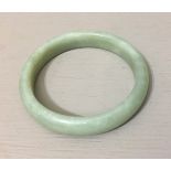 A CHINESE GREEN CELADON JADE BANGLE Of plain circular form, with white inclusions. (inner w 6cm)