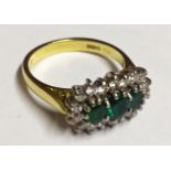AN 18CT YELLOW GOLD AND PLATINUM RING Set with three emeralds surrounded by diamonds (size O).