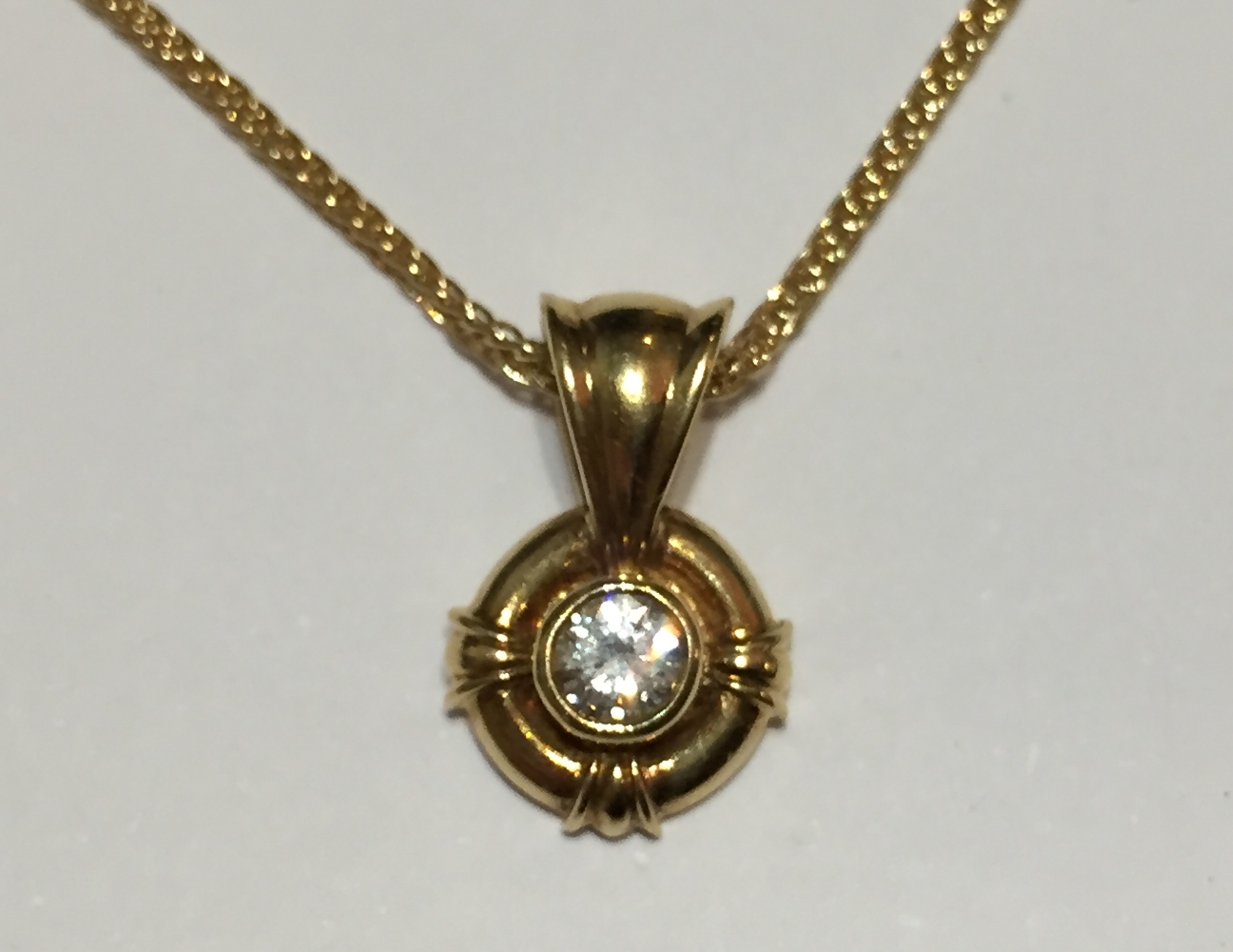 AN 18CT GOLD AND DIAMOND PENDANT The single stone set on a circular clasp, complete with chain.