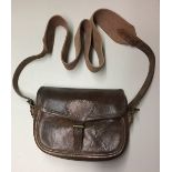 A VINTAGE LEATHER CARTRIDGE BAG With buckle clasp and a webbed canvas strap. (h 17cm x w 27cm)