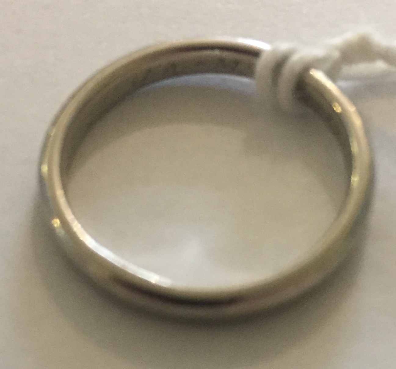 AN EARLY 20TH CENTURY PLATINUM WEDDING BAND Of simple form, the interior with incised initials: 'J.