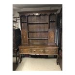 A GEORGIAN OAK DRESSER With an arrangement of open shelves and cupboards above three long drawers,