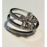 AN 18CT WHITE GOLD AND DIAMOND COIL RING Having a cluster of round cut diamonds forming a flowerhead