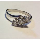 AN 18CT WHITE GOLD AND DIAMOND THREE STONE RING The three round cut diamonds held in a crossover
