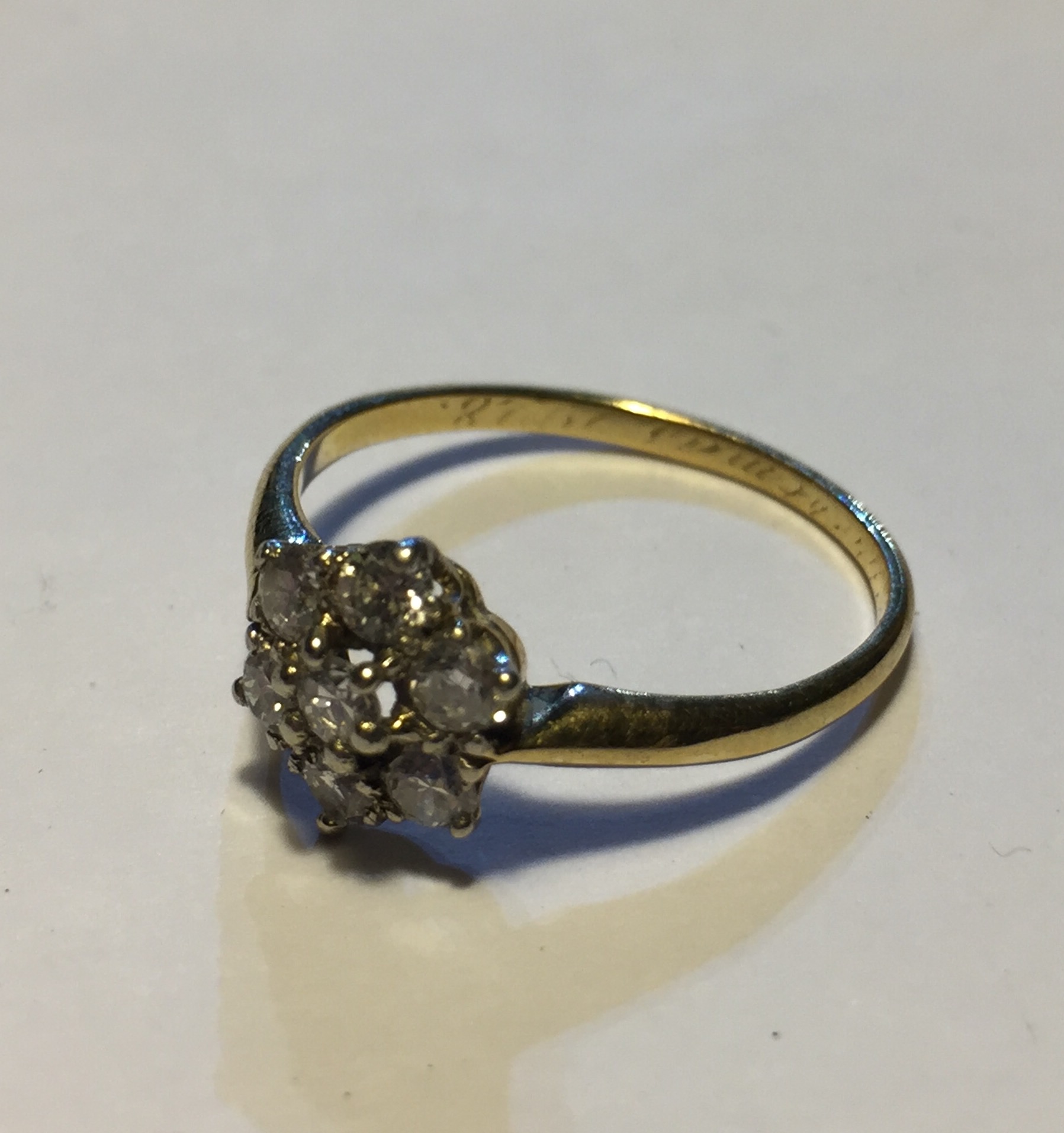 A YELLOW METAL AND DIAMOND DAISY CLUSTER RING Comprising seven round cut diamonds (size Q/R).
