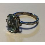AN 18CT WHITE GOLD, DIAMOND AND AQUAMARINE RING Having an oval cut aquamarine flanked by round cut