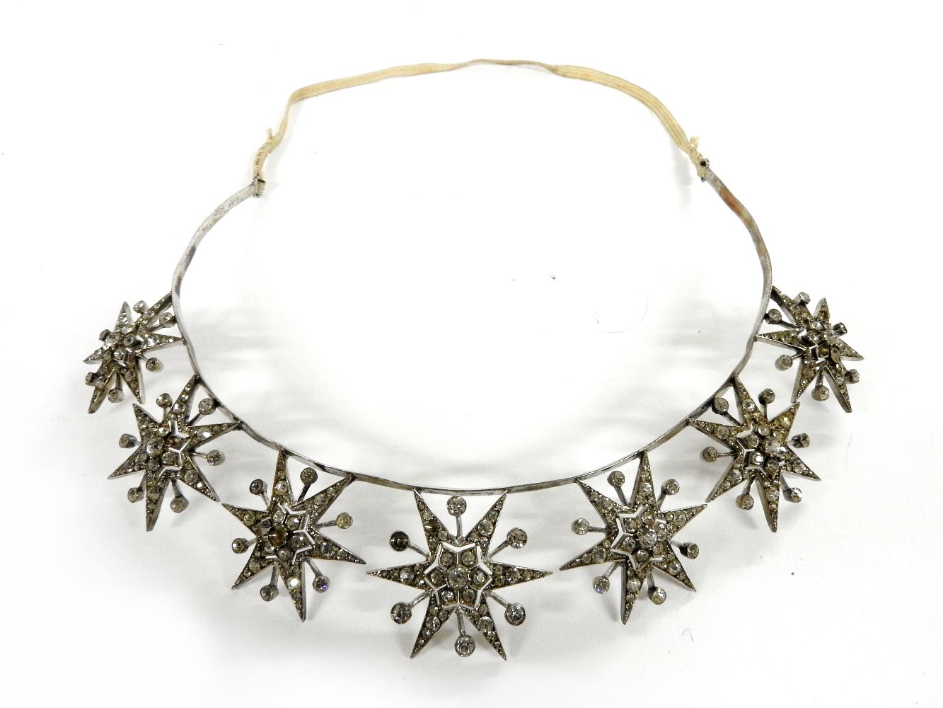 A white metal tiara, set with seven paste stone star bursts, c.1900