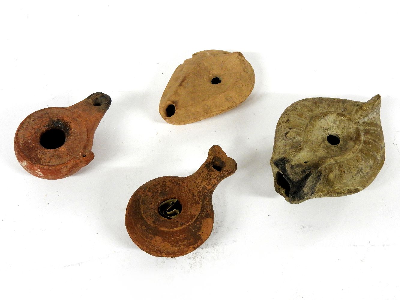 Four various pottery oil lamps, the largest with Gadrooned decoration, 12cm long and three others (