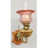 A brass mounted wall oil lamp, with etched cranberry glass shade