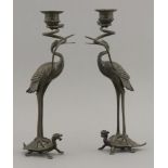 A pair of bronze candlesticks, late 19th century, each crane holding in its beak a coiling serpent