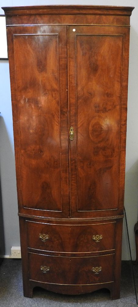 An early 20th century mahogany bow fronted gentleman's robe, on swept feet