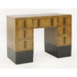 An Art Deco walnut desk, with a black leather tooled top and an arrangement of seven drawers, with