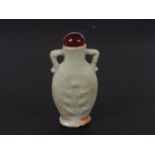 A Chinese qingbai snuff bottle, the oval body moulded with florets, two handles to the neck, 7.4cm