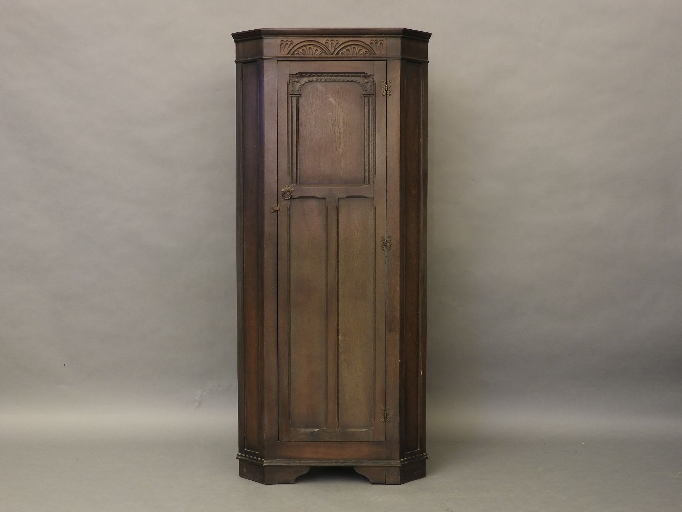 An oak floor standing corner cabinet, with fitted single panel door