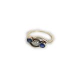 A gold diamond and sapphire three stone crossover ring, 2.31g