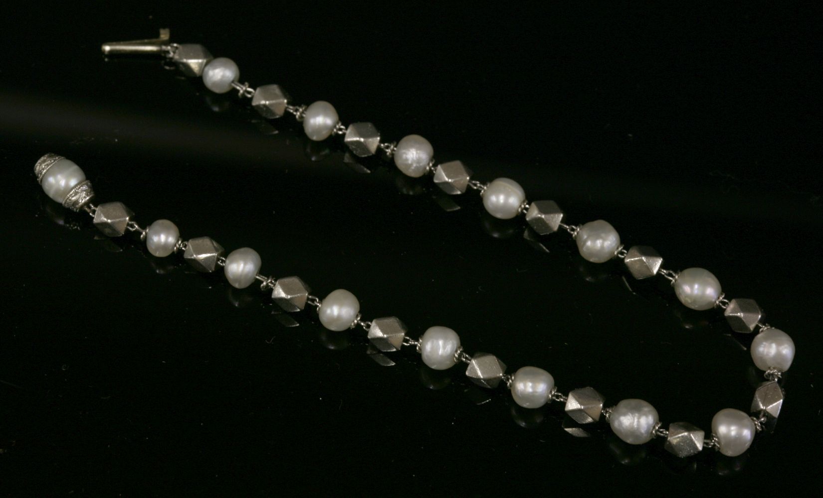An Art Deco platinum and pearl bracelet with series of faceted platinum beads, strung on wire