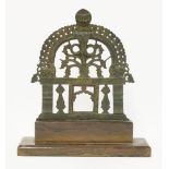 An Indian bronze shrine,possibly 18th century, with a pierced flame aureole surmounted by a mask