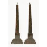 A pair of red granite obelisks,each carved on one side with hieroglyphics, on stepped bases,47cm