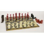 A carved ivory chess set,19th century, stained red and natural,king 8.5cm high,sixteen draughts